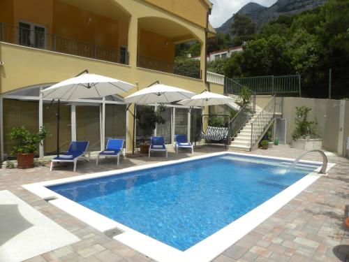 a swimming pool with chairs and umbrellas next to a building at Anka Strman in Makarska