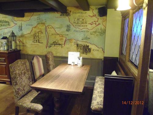 Fountain Inn by Greene King Inns في كاوز: طاولة وكراسي خشبية في غرفة مع خريطة على الحائط