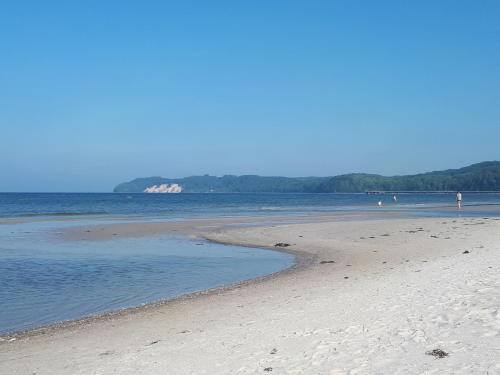 a sandy beach with people walking on the water at Appartement-Villa Steinfurth in Binz