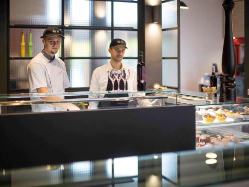 two chefs standing in a kitchen preparing food at Novotel Lille Aéroport in Lesquin