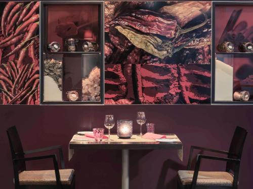 a table with two chairs and a table with wine glasses at Mercure Hotel Düsseldorf Neuss in Neuss