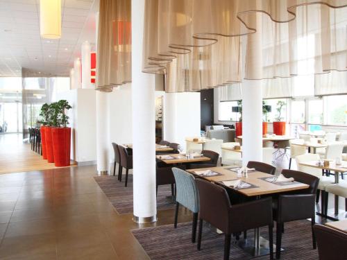 a dining room with tables and chairs in a restaurant at Novotel Brugge Centrum in Bruges