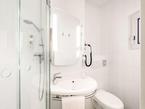 a white bathroom with a sink and a shower at ibis Frankfurt Centrum in Frankfurt/Main
