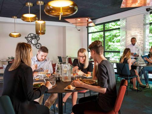 a group of people sitting around a table in a restaurant at Hotel Mercure Blois Centre in Blois