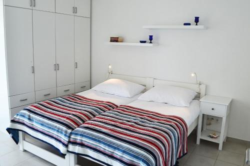 a white bedroom with a bed with a striped blanket at Apartment Viska in Tribunj