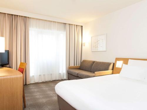 a hotel room with a bed and a couch at Novotel Gent Centrum in Ghent