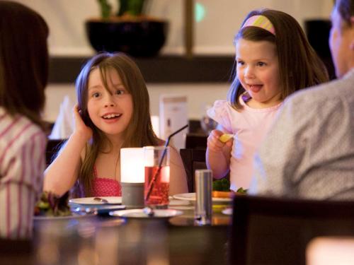 two young girls sitting at a table eating food at Novotel Athens in Athens