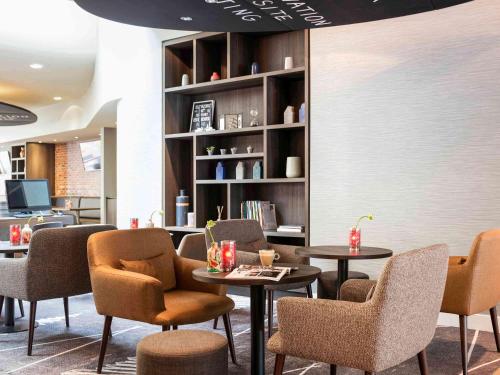 a lobby with tables and chairs and a book shelf at ibis Amsterdam Centre Stopera in Amsterdam