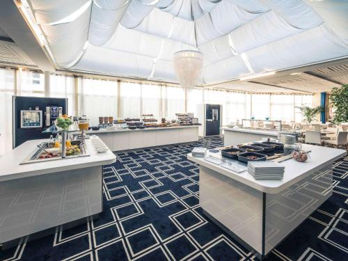 a large kitchen with white counters and a large ceiling at Mercure Montpellier Centre Antigone in Montpellier