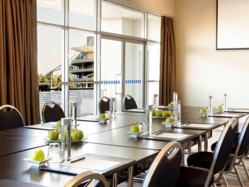 a conference room with long tables and chairs and a large window at ibis Sydney Olympic Park in Sydney