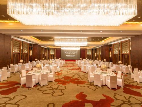 a banquet hall with white tables and chairs and a chandelier at Sofitel Nanjing Galaxy in Nanjing