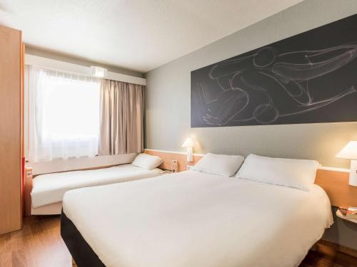 a hotel room with a large white bed and a window at Ibis Granada in Granada