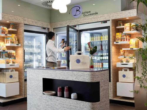 a man standing behind a counter in a store at Novotel Suites Malaga Centro in Málaga