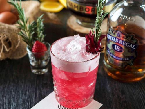 a pink drink on a table with a bottle of alcohol at Pullman Sydney Olympic Park in Sydney