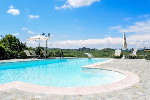 ein großer Pool mit Stühlen und einem Sonnenschirm in der Unterkunft Cascina San Bernardo in Magliano Alfieri