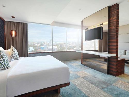 a hotel room with a bed and a flat screen tv at Novotel Makassar Grand Shayla in Makassar