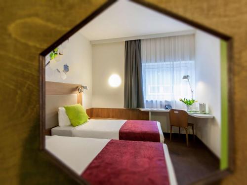 a hotel room with a bed and a desk at Ibis Styles Vilnius in Vilnius