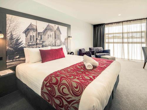 a bedroom with a large bed with a red and white blanket at Mercure Warragul in Warragul