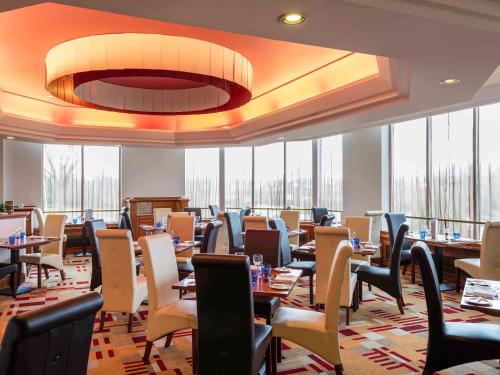 a dining room with tables and chairs and windows at Mercure Daventry Court Hotel in Daventry