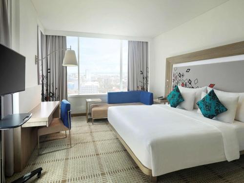 a hotel room with a large bed and a desk at Novotel Makassar Grand Shayla in Makassar