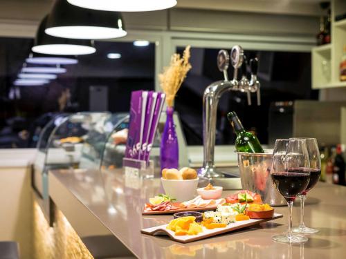 a counter with two glasses of wine and food at Novotel Santos Gonzaga in Santos