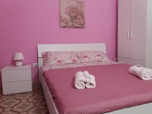ein rosafarbenes Schlafzimmer mit Handtüchern auf dem Bett in der Unterkunft A casa di Alba in Marsala