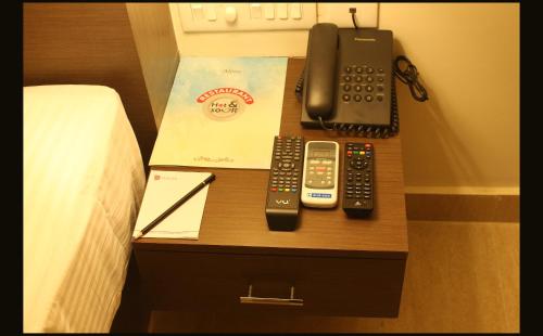 a bedside table with a telephone and remote controls at Hotel Yamuna in Adūr