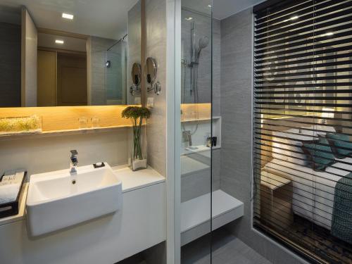 
a bathroom with a tub, sink and mirror at Solitaire Bangkok Sukhumvit 11 - SHA Extra Plus in Bangkok
