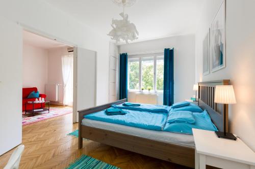 a bedroom with a bed with blue sheets and a window at Rubinstein Relax Apartman in Budapest