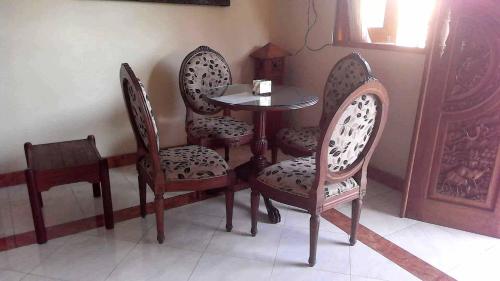 einen Tisch und drei Stühle sowie einen Tisch und Stühle in der Unterkunft The Reinhold Guesthouse Bali in Kerobokan