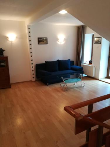 a living room with a blue couch and wooden floors at Arsenal Park Transilvania in Orăştie