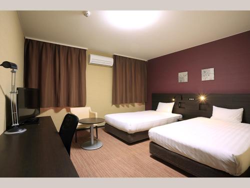 a hotel room with two beds and a desk at Smile Hotel Otsu Seta in Otsu