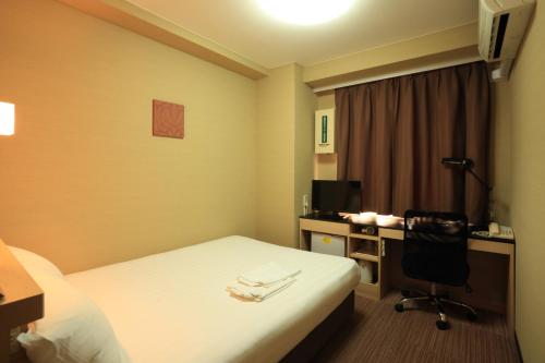 a hotel room with a bed and a desk with a computer at Smile Hotel Otsu Seta in Otsu