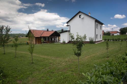 a large white house in a field with trees at Rooms Ivan in Otočac