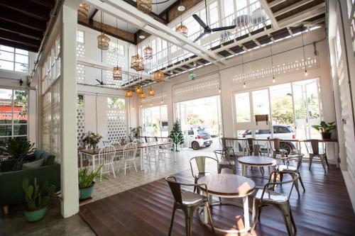 un restaurante con mesas y sillas en una habitación con ventanas en Memmoth Hostel In Lampang, en Lampang