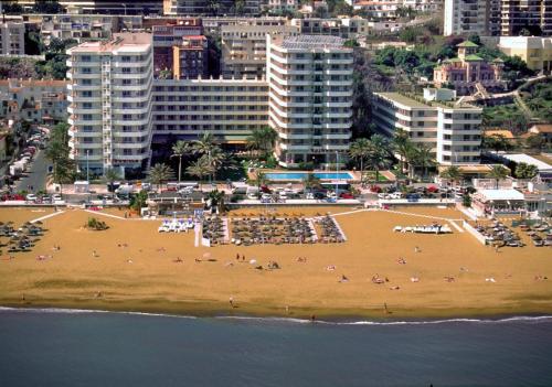 a beach with palm trees and palm trees at Hotel Apartamentos Bajondillo in Torremolinos