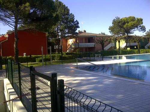 a swimming pool with a fence next to a building at Adriella apartments in Bibione