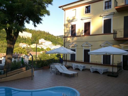 a patio with tables and umbrellas in front of a building at Raffaello Residence in Sassoferrato