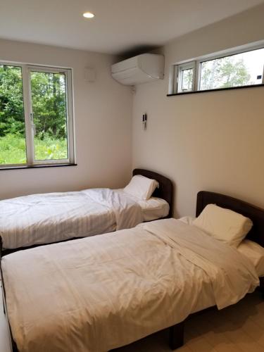 Furano Mount Villa في فورانو: سريرين في غرفة بها نافذتين