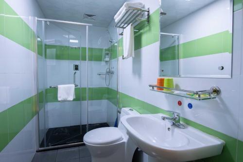 a green and white bathroom with a toilet and a sink at Orange Fashion Apartment Hotel Guangzhou Xiajiao Subway Station Branch in Guangzhou