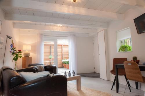 豪達的住宿－Het Suikerpandje，客厅配有皮革家具和桌子
