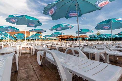 a bunch of white chairs and umbrellas on a beach at SPA Kompleks Raiski Kat in Dimitrovgrad