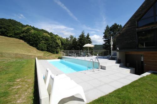 uma casa com piscina ao lado de um edifício em La Colline Du Baa - Maison d'hôtes d'exception em Lapoutroie