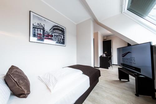 a bedroom with a bed and a flat screen tv at Mauritius Hotel & Therme in Cologne