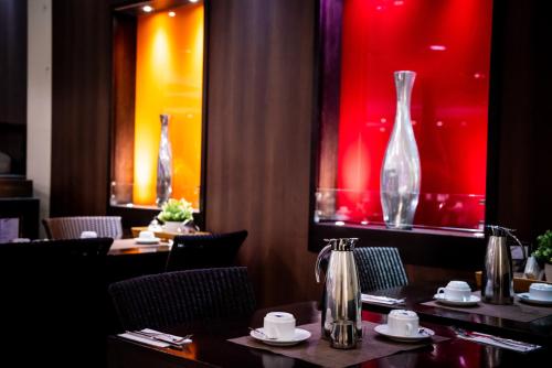 a restaurant with two tables and two glass vases at Mauritius Hotel & Therme in Cologne