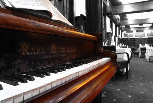 a piano in a room with tables and chairs at Brioni Suites in Ostrava
