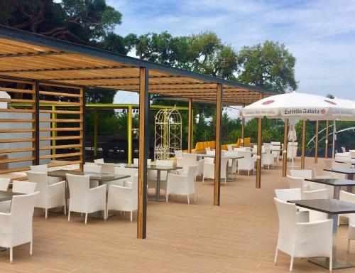 マルベーリャにあるRoyal Tennis Clubのテーブル、白い椅子、パラソルが備わるレストラン