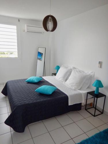 ein Schlafzimmer mit einem großen Bett und blauen Kissen in der Unterkunft Au Petit Paradis in Sainte-Anne
