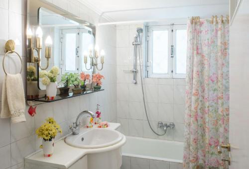 La salle de bains blanche est pourvue d'un lavabo et d'une douche. dans l'établissement Family apt with garden next to the sea, à Athènes