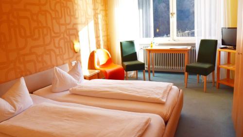 a hotel room with two beds and a desk and chairs at Hotel Paulanerstuben in Wasserburg am Inn